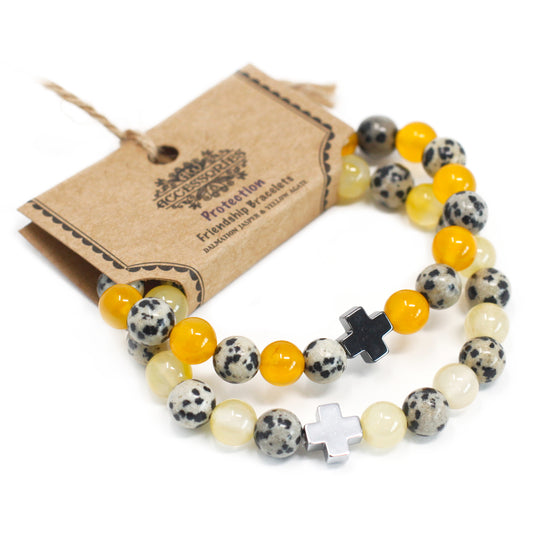 Dos pulseras de piedras preciosas amarillas y blanco dálmata con una cruz plateada en soporte de cartón para colgar