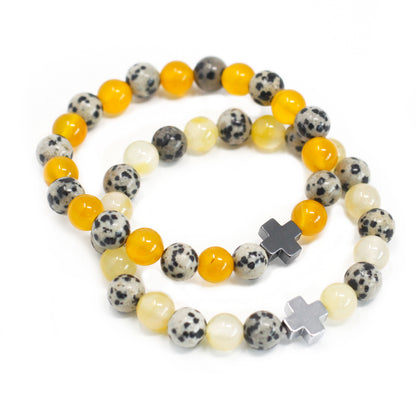 Dos pulseras de piedras preciosas amarillas y blanco dálmata con una cruz plateada