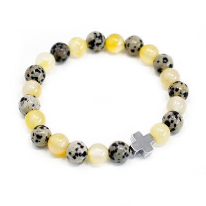 Una pulsera de piedras preciosas amarillas y blanco dálmata con una cruz plateada